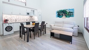 Un espacio habitable compacto con kitchenette, comedor y sofá.