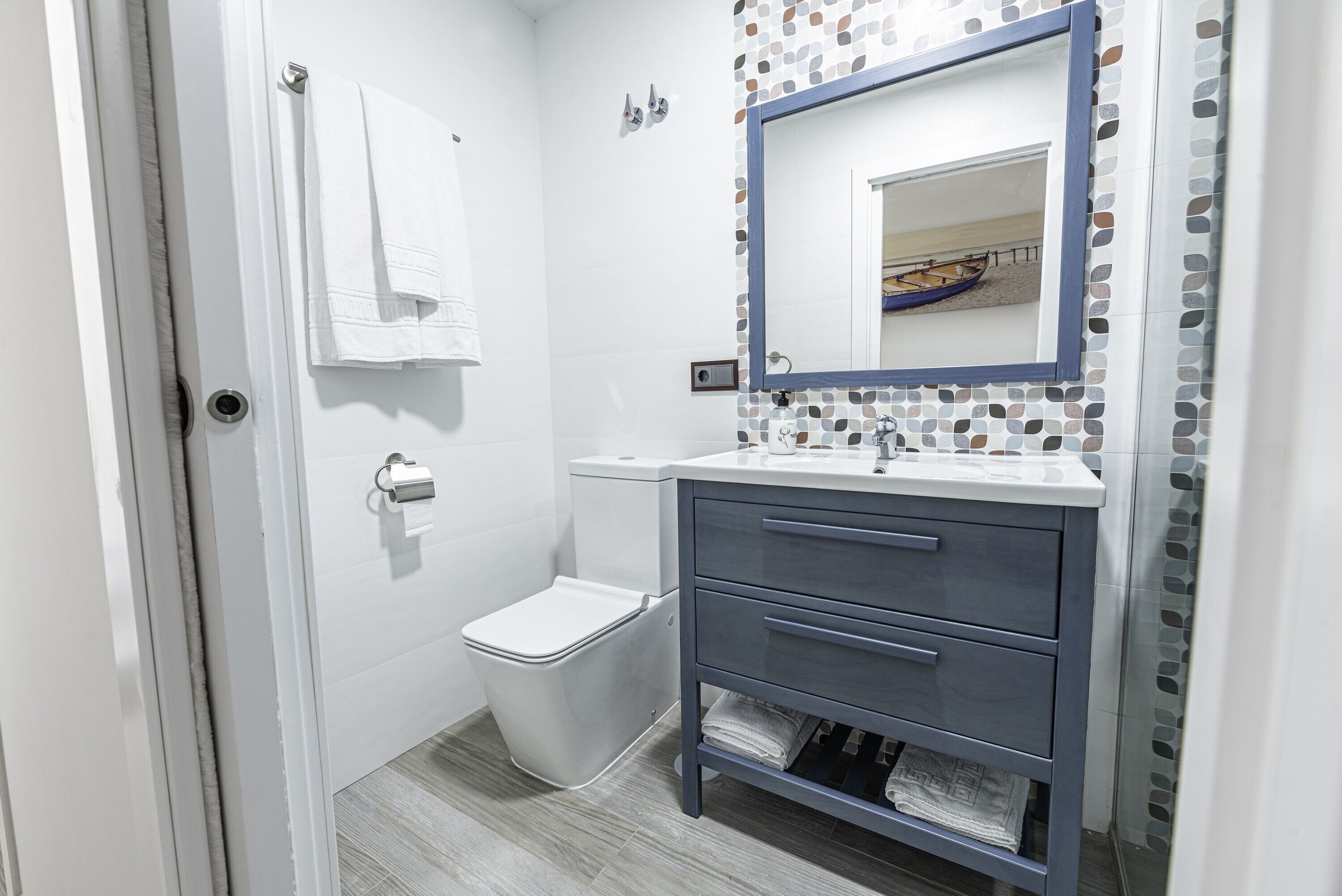 A bathroom with a white toilet, a sink with a mirror, and a tiled backsplash.