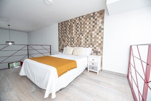 A modern bedroom with a bed, bedside table, and a geometric-patterned wall.