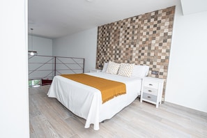 Une chambre moderne avec un grand lit, une tête de lit en bois, une table de chevet avec des tiroirs et une vue sur l’extérieur.