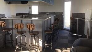 Una cocina moderna con taburetes de bar, un reloj grande y una ventana.