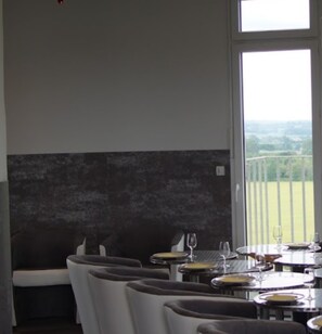 A dining area with multiple tables and chairs, a view of a green landscape through large windows. - Pet-Friendly Castle "chateau d'eau le sable" with Balconies & Wi-Fi (DAON)