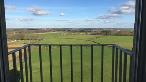 Un balcón con vistas a un campo verde y edificios lejanos.