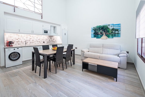 A compact living space with a kitchenette, dining area, and a sofa.
