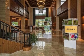 A spacious lobby with a polished floor, wooden accents, a staircase, and a display of framed pictures. - Golf Hotel Wuhan Yishan (Wuhan)
