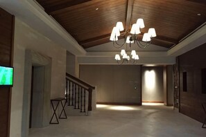 A hallway with a wooden ceiling, a chandelier, a television, and a staircase. - Golf Hotel Wuhan Yishan (Wuhan)