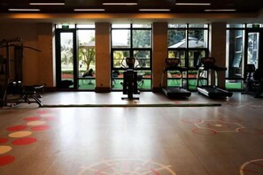 Een sportschool met fitnessapparatuur, grote ramen en een vloer met een patroon.