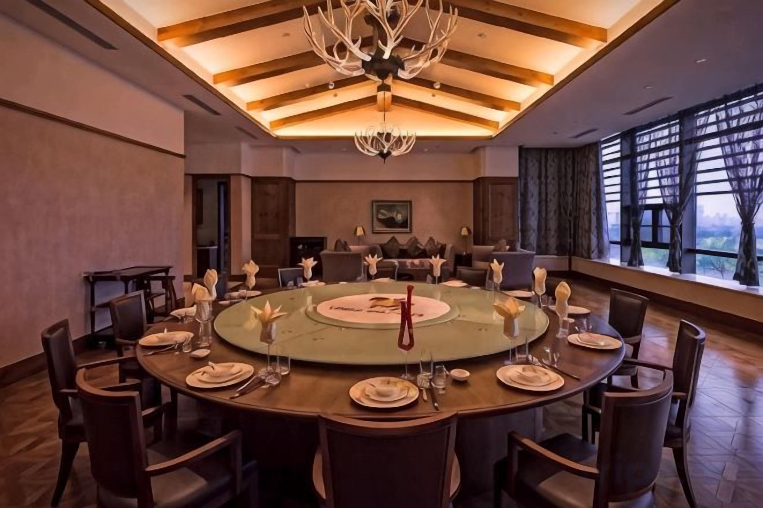 A conference room with a round table, chairs, and a chandelier.