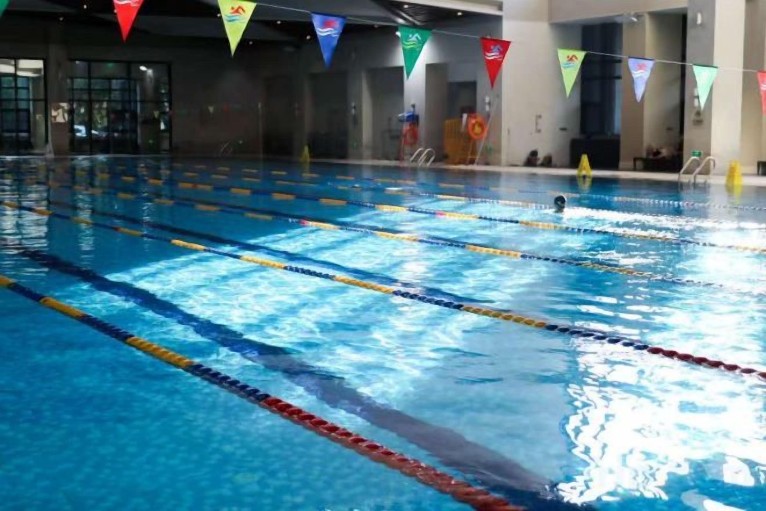 A swimming pool with multiple lanes and a tiled floor.