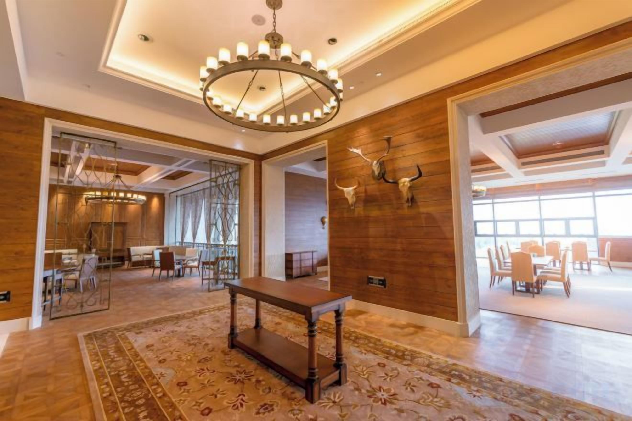 Un vestíbulo amplio con piso de madera, una mesa central y un candelabro.