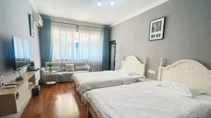 Habitación de hotel con dos camas, televisión, escritorio, silla y ventana con cortinas.