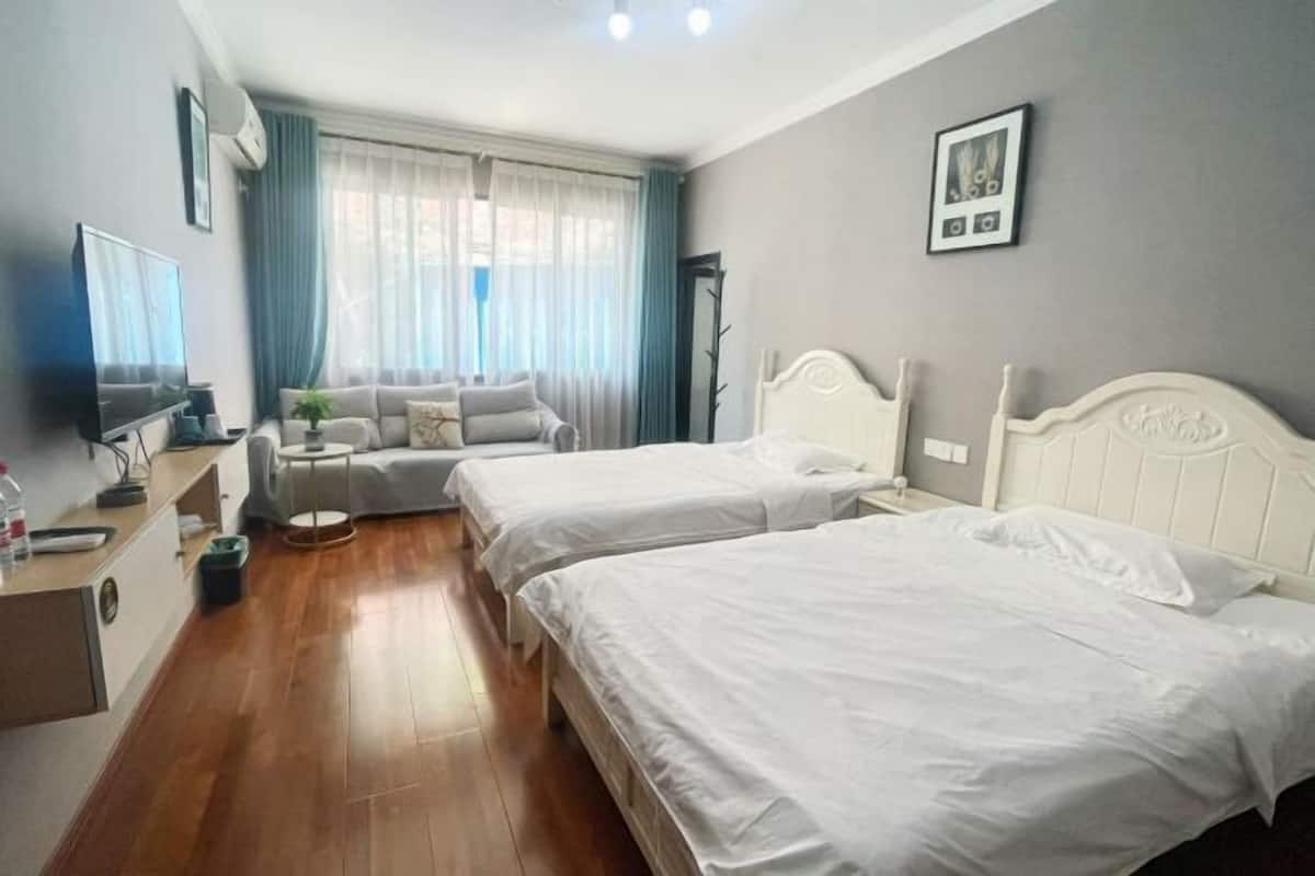 Ein Hotelzimmer mit zwei Betten, einem Fernseher, einem Schreibtisch, einem Stuhl und einem Fenster mit Vorhängen.