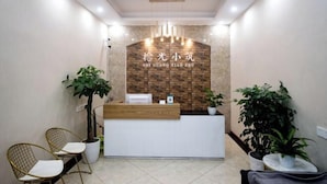 Zona de recepción con pared de ladrillo, mostrador de madera y dos sillas.