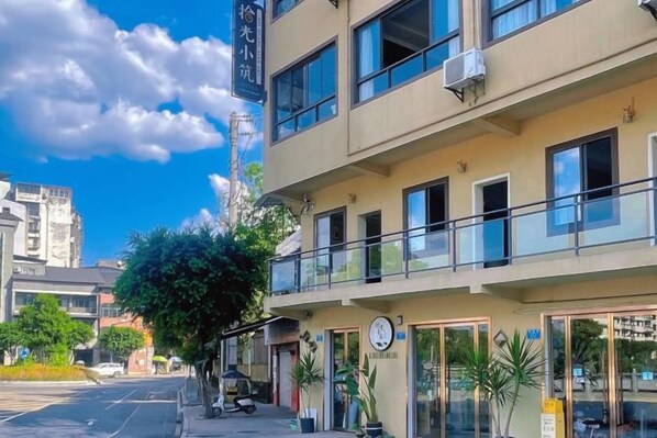 A multi-story building with a balcony on the second floor, a clock, and a sign with a number.