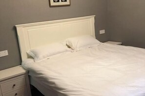 A neatly made bed with white bedding and a matching headboard in a room with light gray walls. - Shiguang Xiaozhu Nordic Guesthouse (Chongqing)