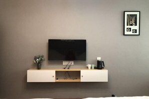A modern room with a mounted TV, a small coffee station, and a framed picture on the wall. - Shiguang Xiaozhu Nordic Guesthouse (Chongqing)