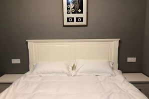 A neatly made bed with white bedding, a white headboard, and a framed picture on the wall. - Shiguang Xiaozhu Nordic Guesthouse (Chongqing)