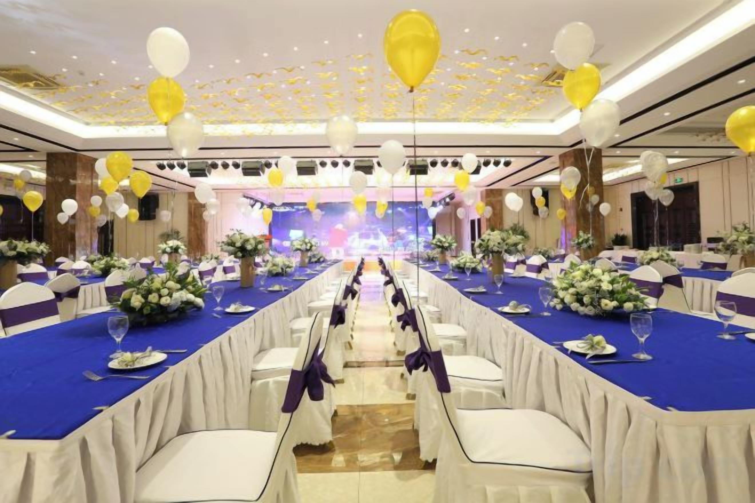 A banquet hall with tables set for a formal event, featuring a stage in the background.