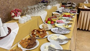 Un tavolo da buffet con diversi cibi e utensili, una telecamera di sicurezza a parete e un dipinto di un paesaggio.