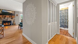 Ein Wohnzimmer mit Kamin aus Stein, einem Fernseher und einer Wand mit Muster.