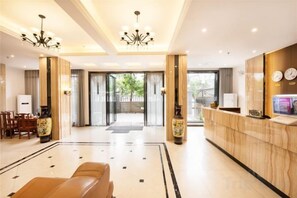 Un hall d’hôtel comprenant un comptoir d’accueil, un espace salon et une vue à travers les portes vitrées.