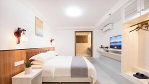 A hotel room with a bed, bedside table, TV, and a view of the city. - Xiaoshu Wushe Boutique Hostel (Haikou)