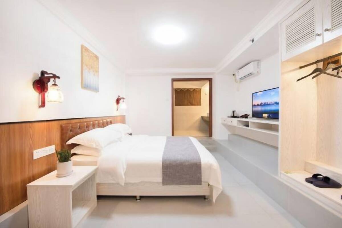 Ein Hotelzimmer mit Bett, Nachttisch, Fernseher und Blick auf die Stadt.