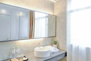 A modern bathroom with a large mirror, a round sink, and a countertop with toiletries. - Xiaoshu Wushe Boutique Hostel (Haikou)