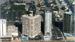 Un edificio alto con varios pisos, un estacionamiento y un río al fondo.