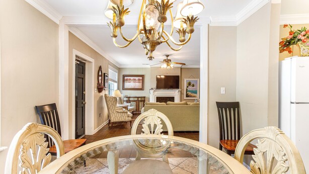 Un comedor con una mesa de vidrio, sillas ornamentadas, una araña y vistas al salón.