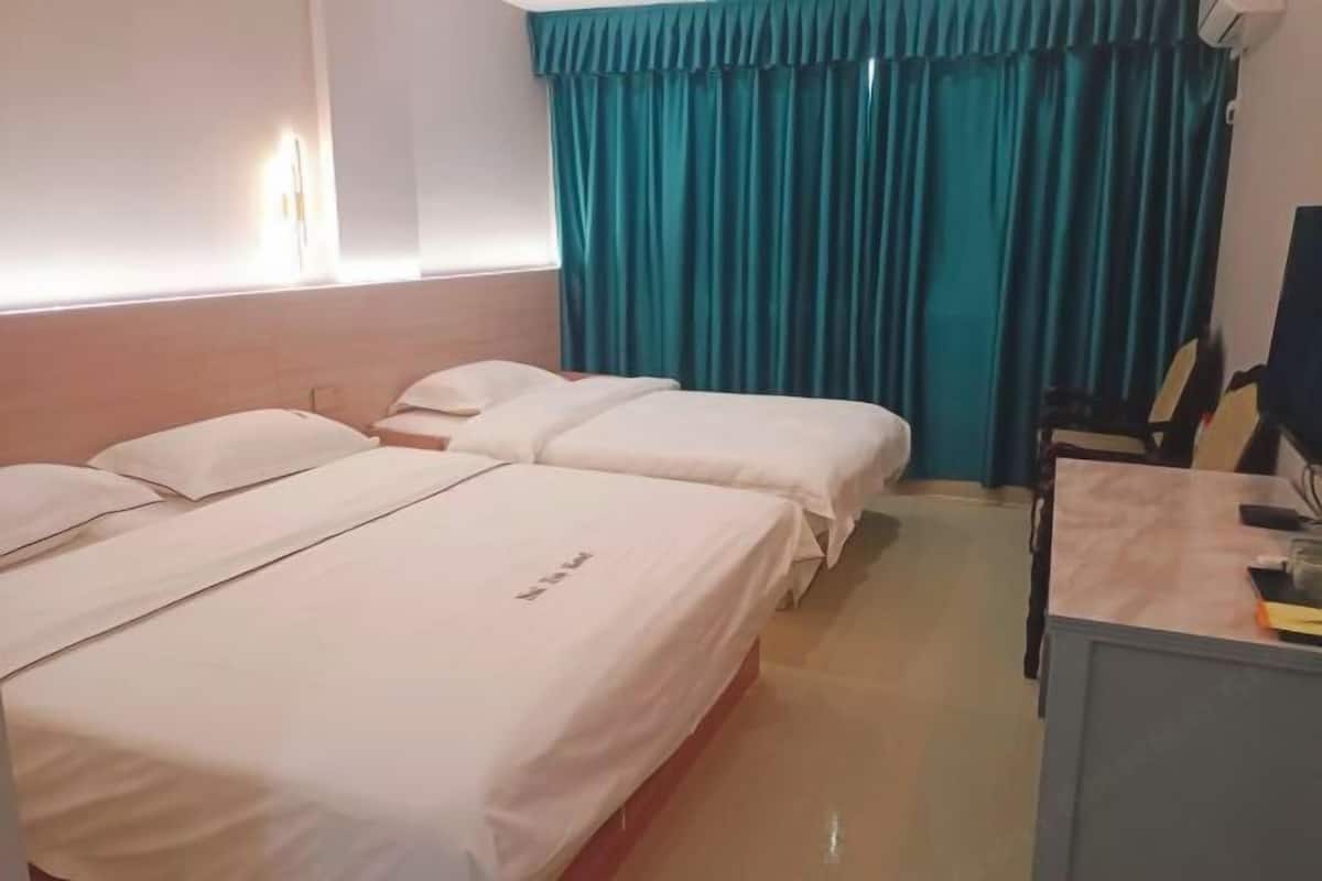 A hotel room with two beds, a desk, and a chair.