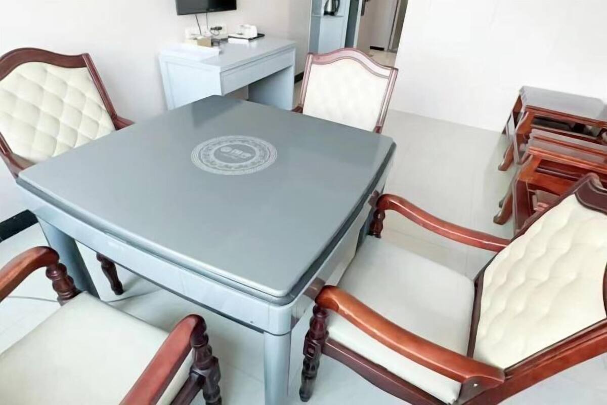 A dining area with a grey table, wooden chairs, and a white cabinet.