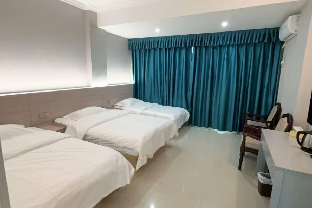 A hotel room with two beds, a desk, a chair, and a window with curtains.