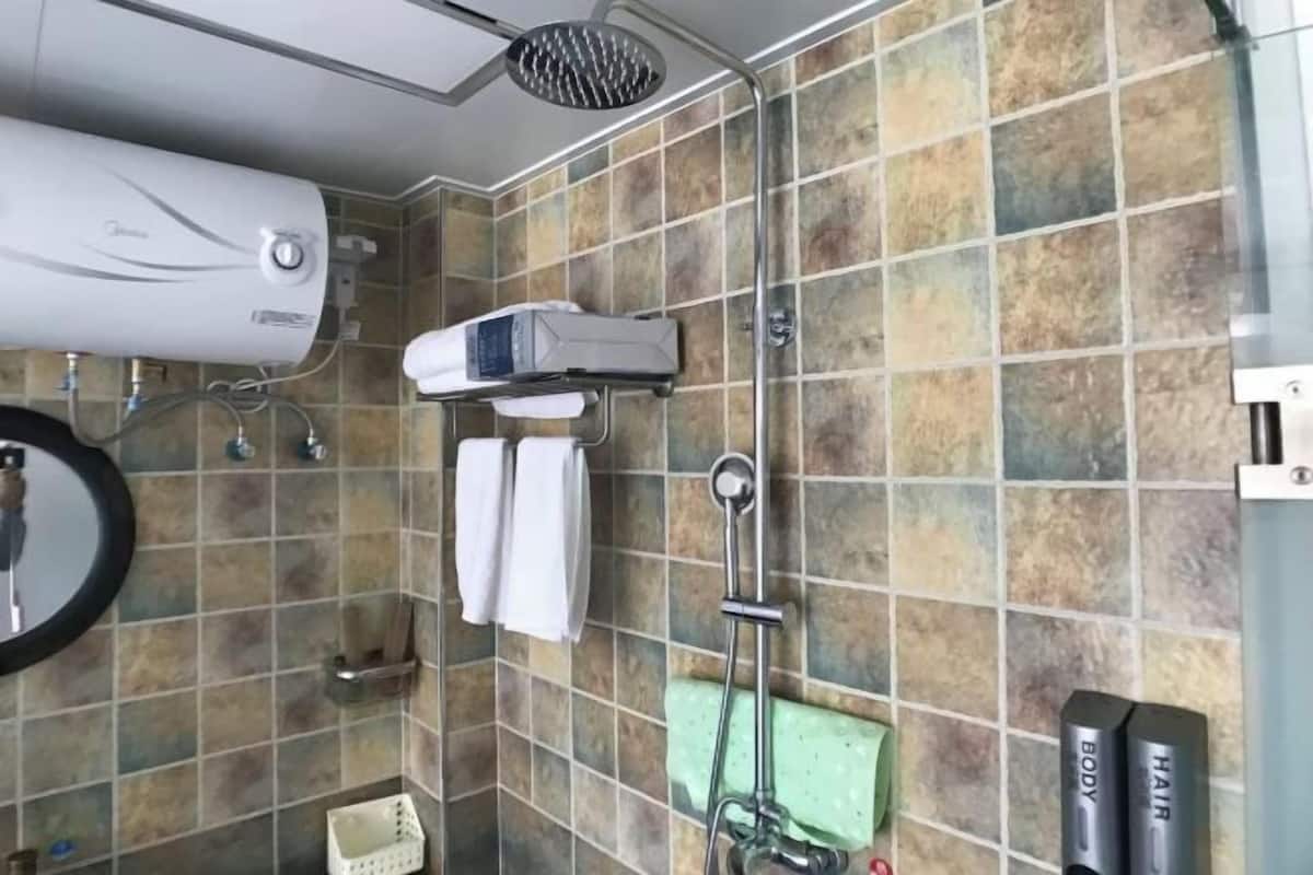 A bathroom with a shower, a towel rack, a mirror, and a wall-mounted heater.