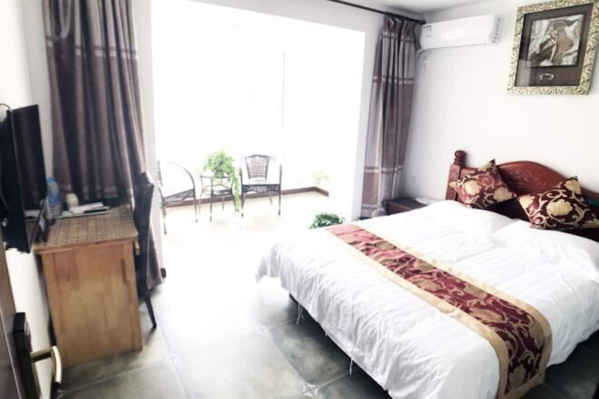 A hotel room with a bed, a desk, a chair, and a view of the outside.