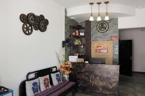 A reception area with a wooden reception desk, a bench with decorative pillows, and a wall-mounted clock. - Fushun ala warm hotel (Fushun)