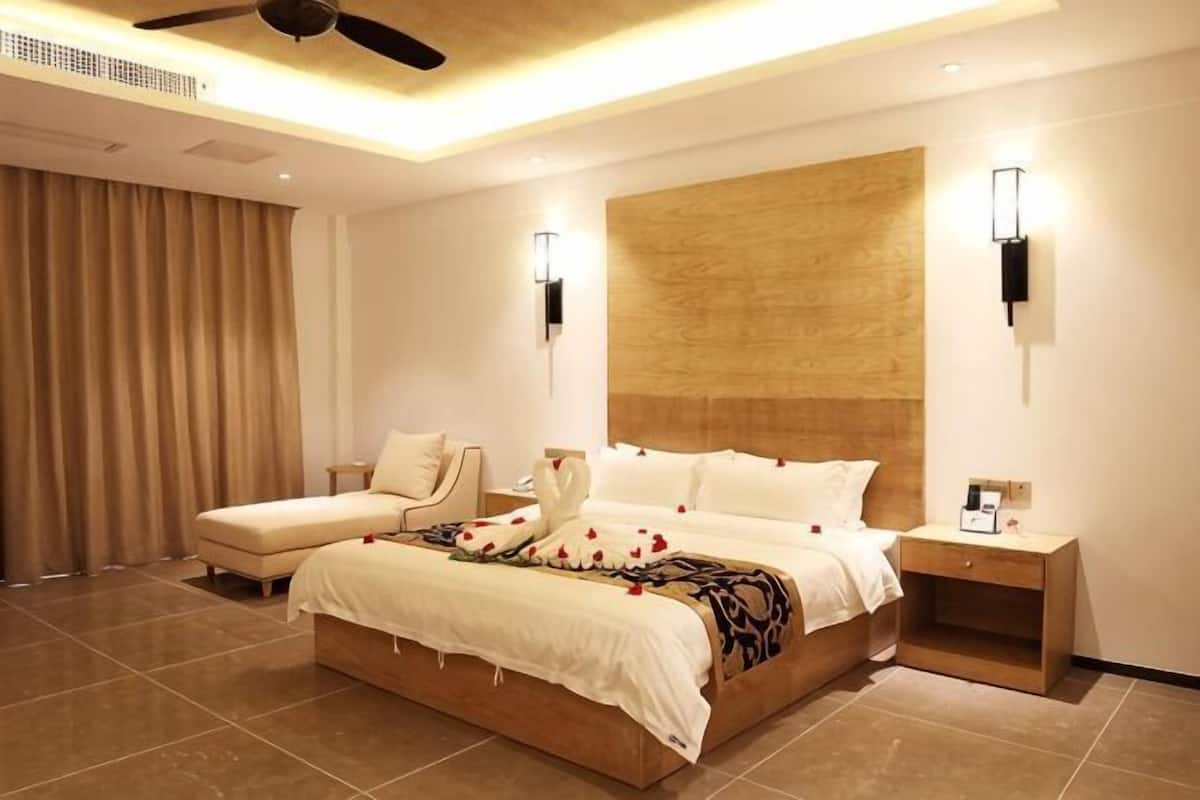 Un dormitorio moderno con una cama grande, una mesita de noche, un ventilador de techo y una lámpara de pared.