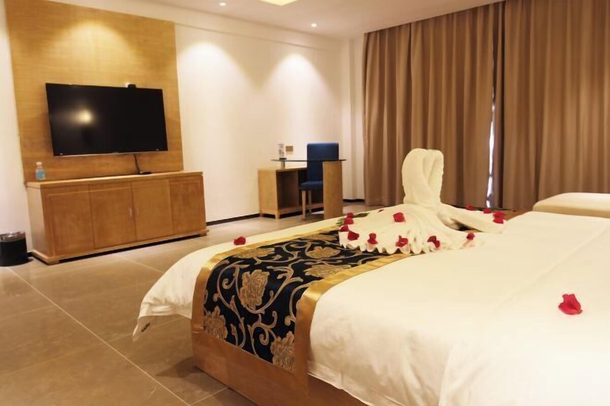 Een hotelkamer met een bed, een aan de muur bevestigde televisie, een bureau en een stoel.