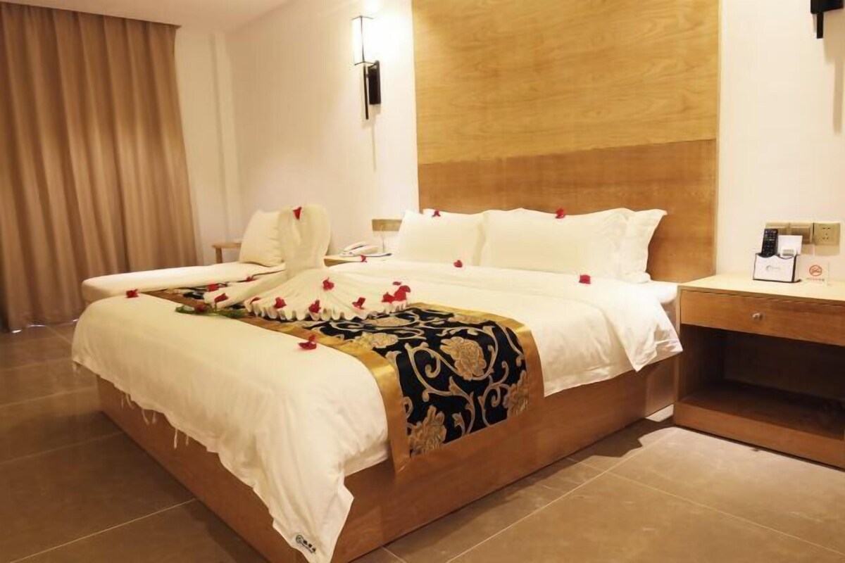 Een hotelkamer met een groot bed, een nachtkastje en een houten hoofdeinde.