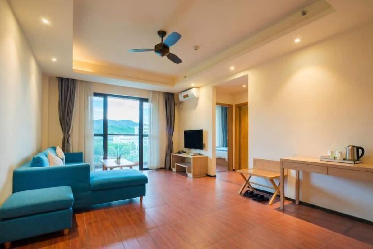 Habitación de hotel moderna con sofá, televisor, escritorio y vistas al exterior.