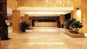 A spacious lobby with a marble floor, wooden reception desk, and potted plants. - Yabulun Health & Wellness Holiday Hotel (Sanya)