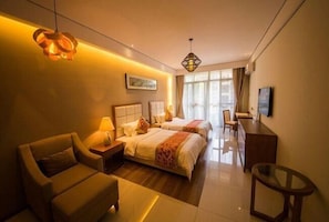 Ett hotellrum med två sängar, en soffa, ett skrivbord och en TV.