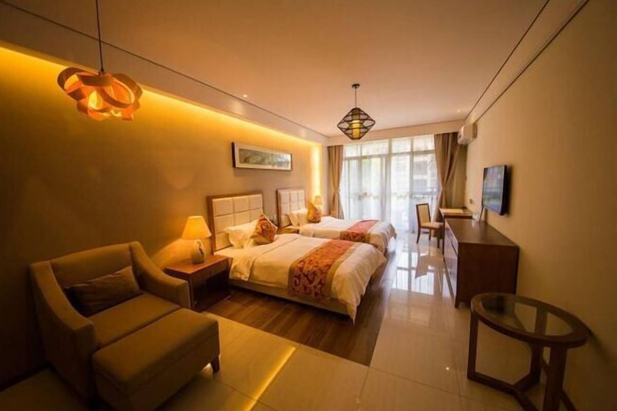 Habitación de hotel con dos camas, un sofá, un escritorio y un televisor.
