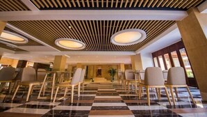 A hotel lobby with a checkered floor, wooden chairs, and a modern ceiling design. - Yabulun Health & Wellness Holiday Hotel (Sanya)