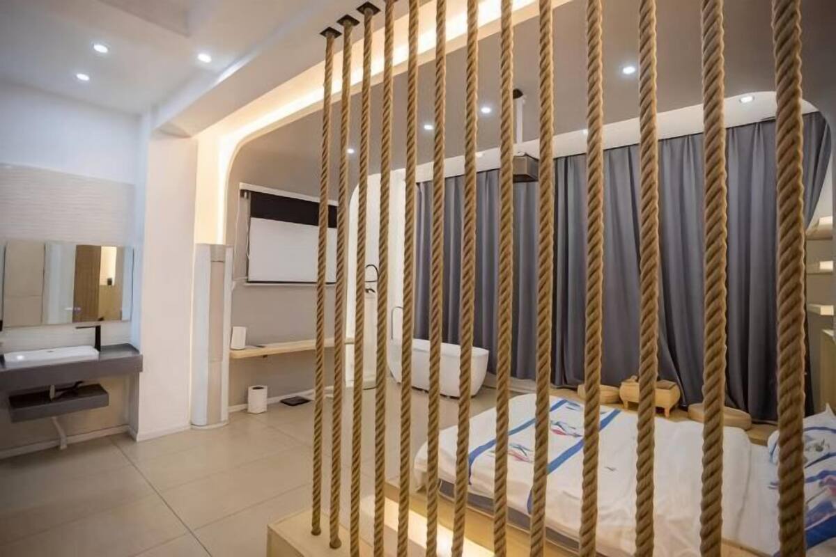 A modern bedroom with a bed, a desk, and a large mirror.