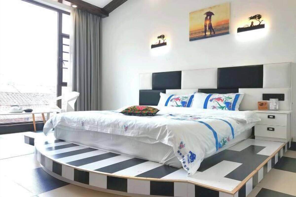 A modern bedroom with a curved bed, a view of the city, and artwork on the walls.