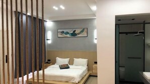 Un dormitorio moderno con cama, mesitas de noche, un cuadro y baño con ducha.