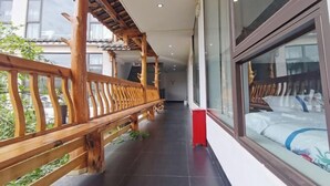 Un pasillo con barandillas de madera, una cama con ventana y un armario rojo.