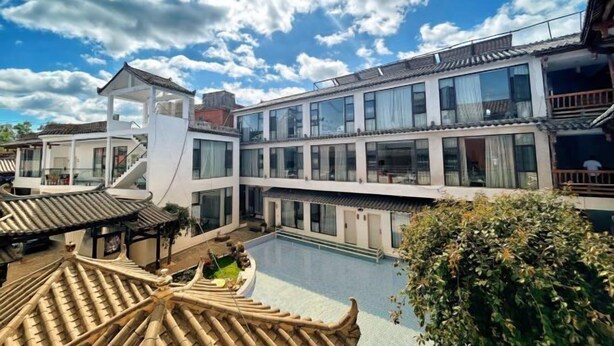 Un edificio tradicional con una extensión moderna, un patio con piscina y un tejado al estilo pagoda.