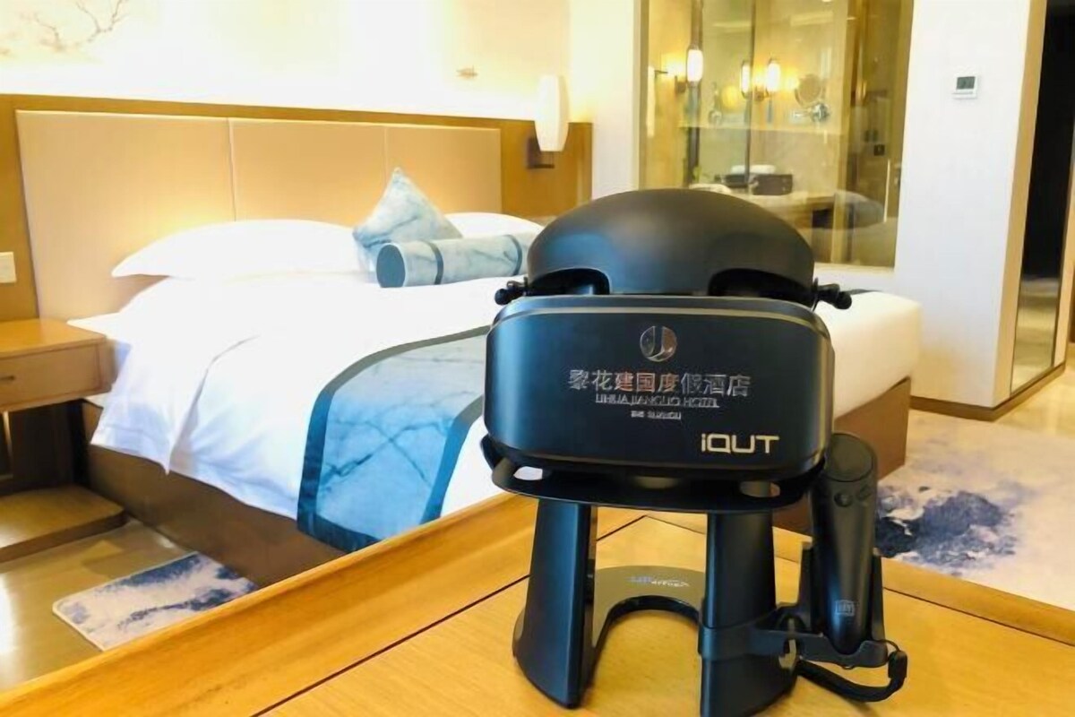 Een hotelkamer met een bed, een nachtkastje en een modern zwart apparaat op de vloer.